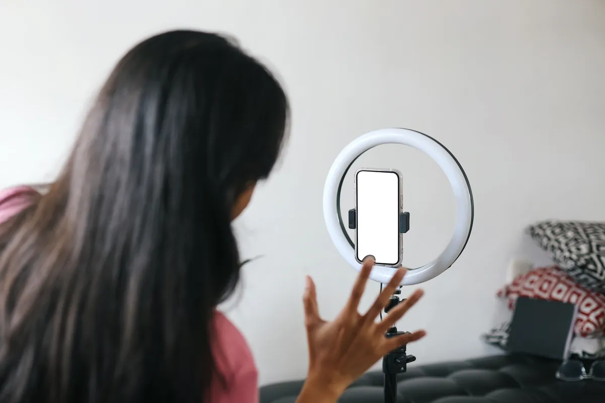 Créatrice de contenu filmant avec un smartphone fixé sur un anneau lumineux