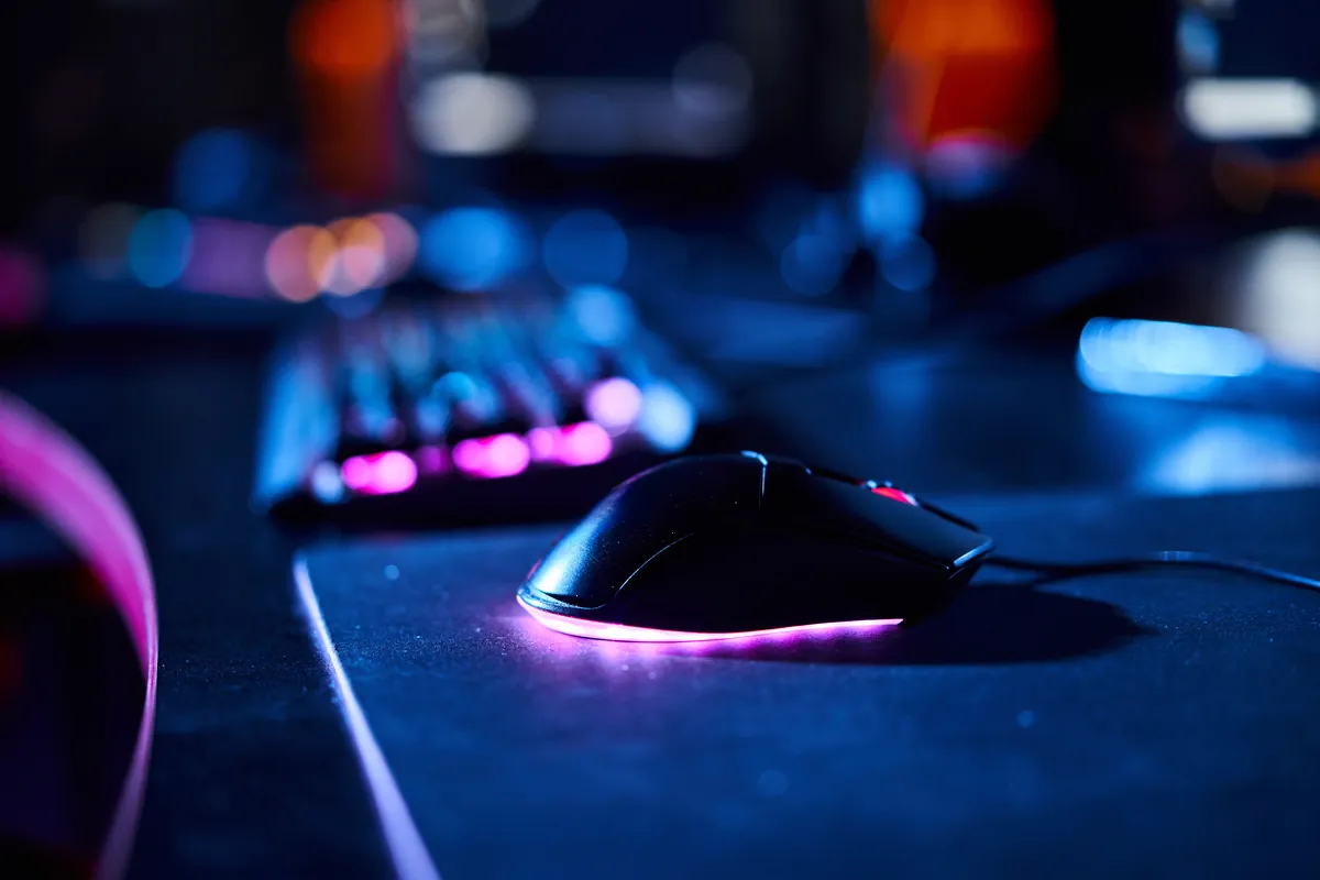 Souris gaming et clavier rétroéclairés sur un bureau sombre aux lumières néon