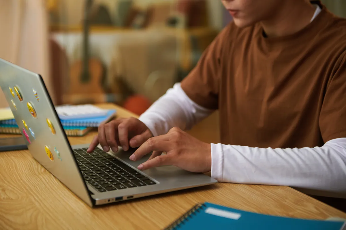 Adolescent travaillant sur un ordinateur portable à son bureau pour suivre ses cours en ligne