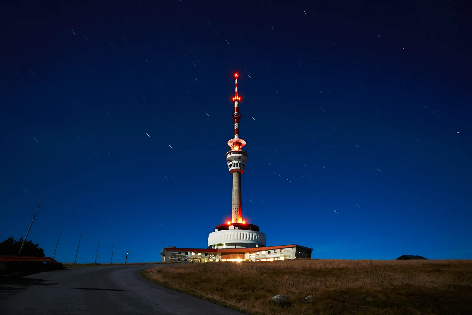 Tour de télécommunication illuminée sur une colline sous un ciel étoilé